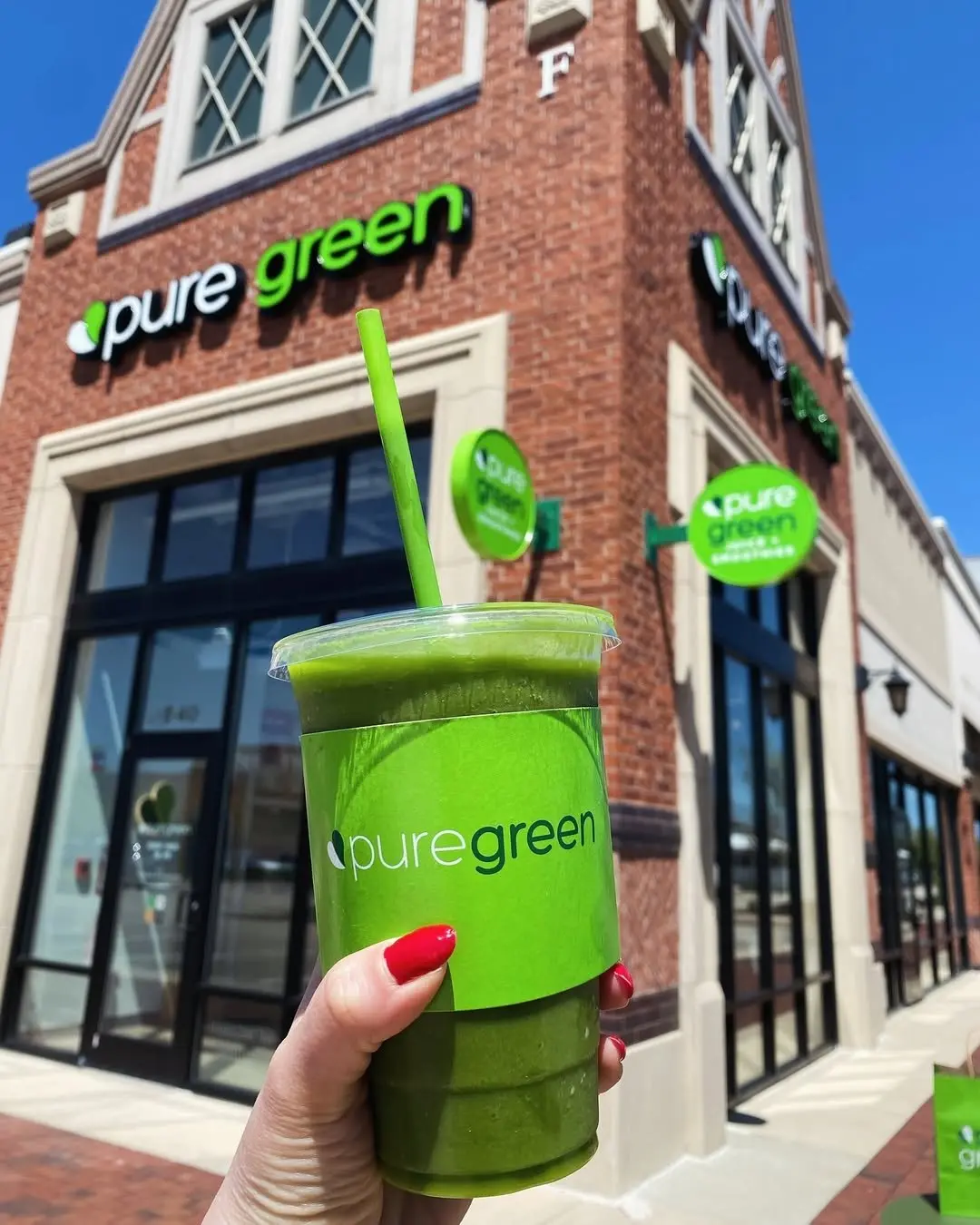A green smoothie held up outside Pure Green South Barrington