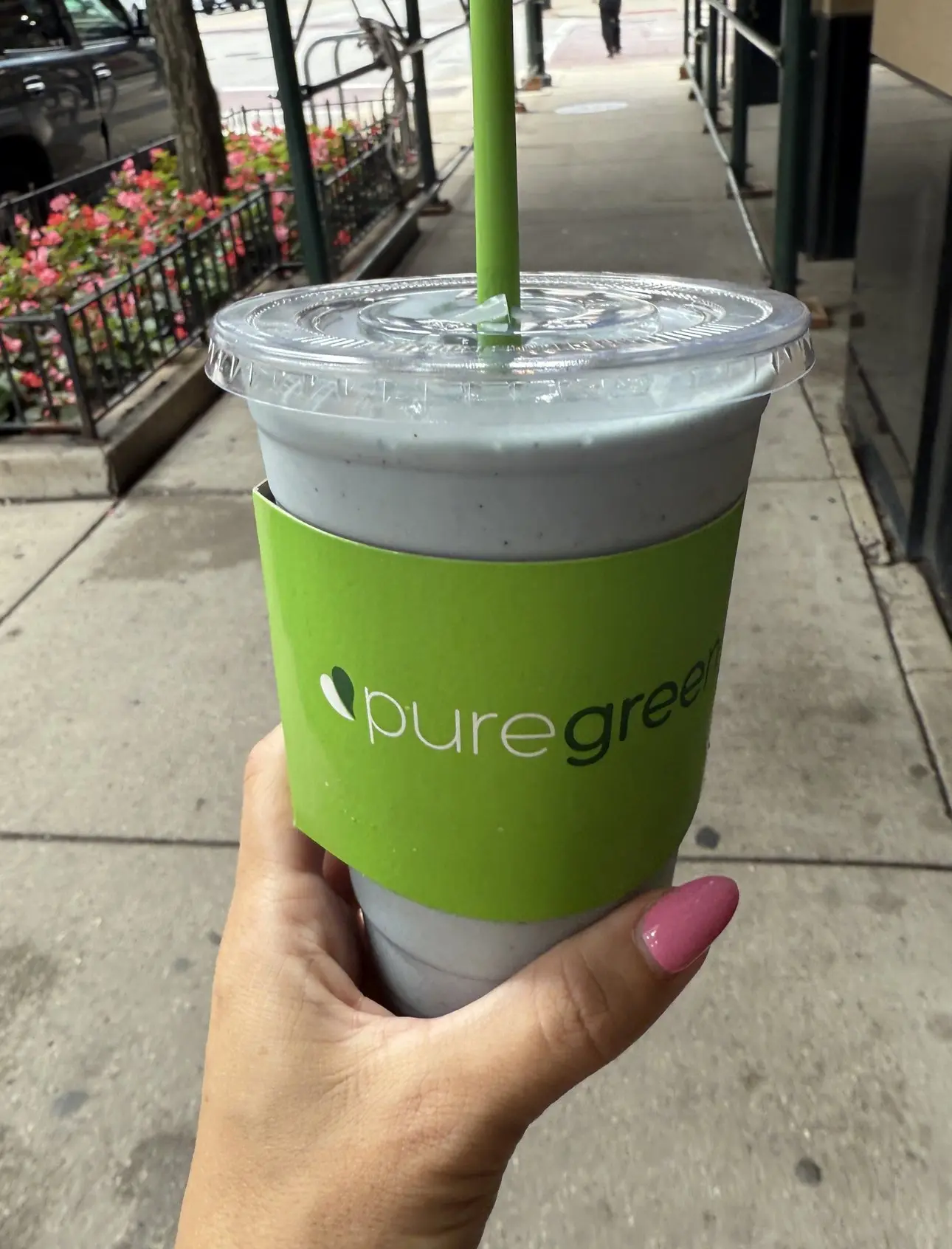 A green smoothie held up on the sidewalk outside Pure Green South Michigan Ave