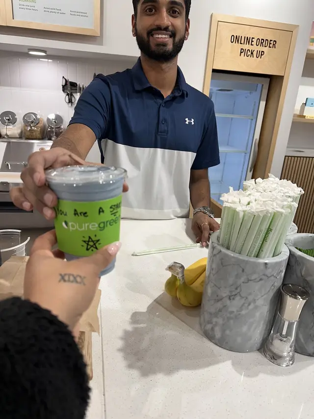 A team member handing over a smoothie at Pure Green Buckhead Crossing