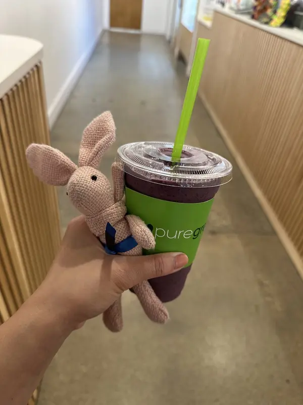 Guest holding a fresh Pure Green smoothie at Mizner Park