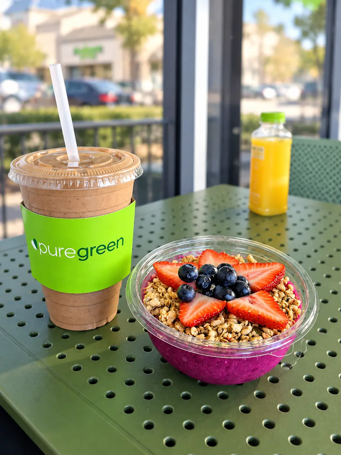 Smoothie and berry-topped bowl on a green table at Pure Green Arcadia