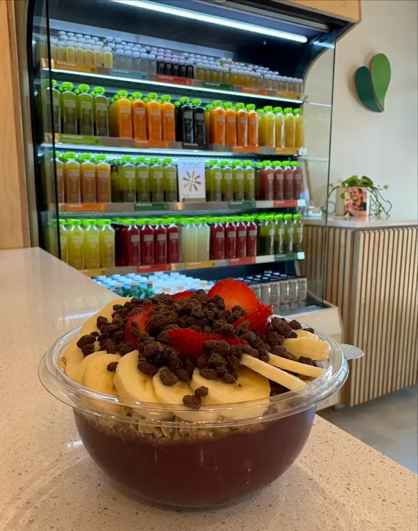 Acai bowl in front of the cold-pressed juice fridge at Pure Green Aventura