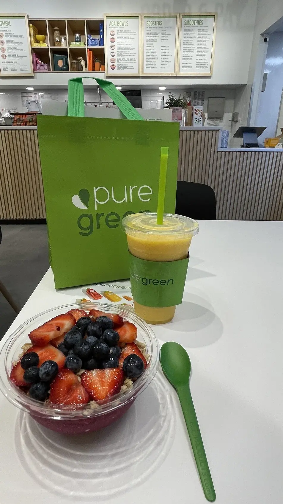 An acai bowl, a smoothie and a Pure Green tote on the counter at Pure Green River North