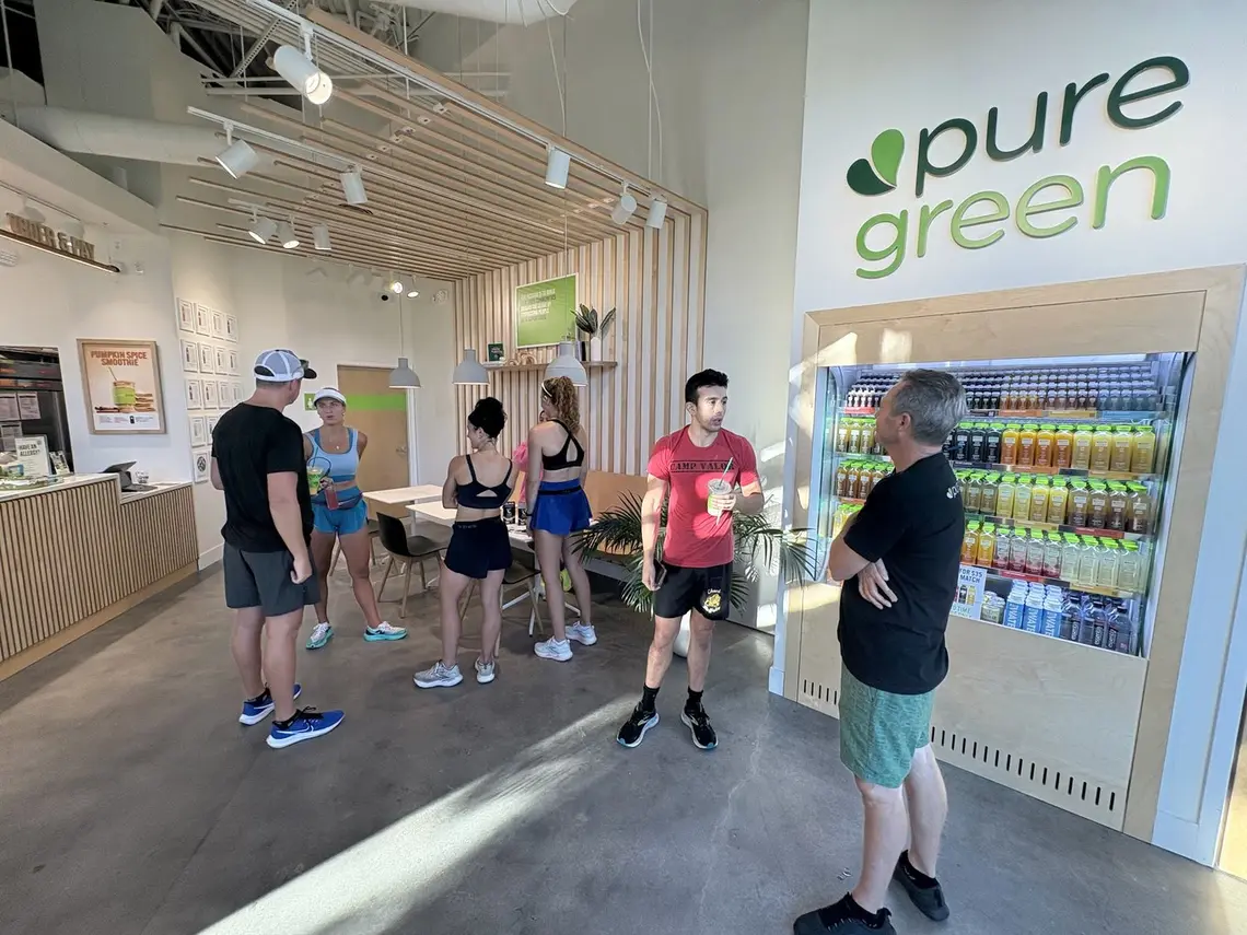 Guests at the counter and the cold-pressed juice fridge inside Pure Green North Naples
