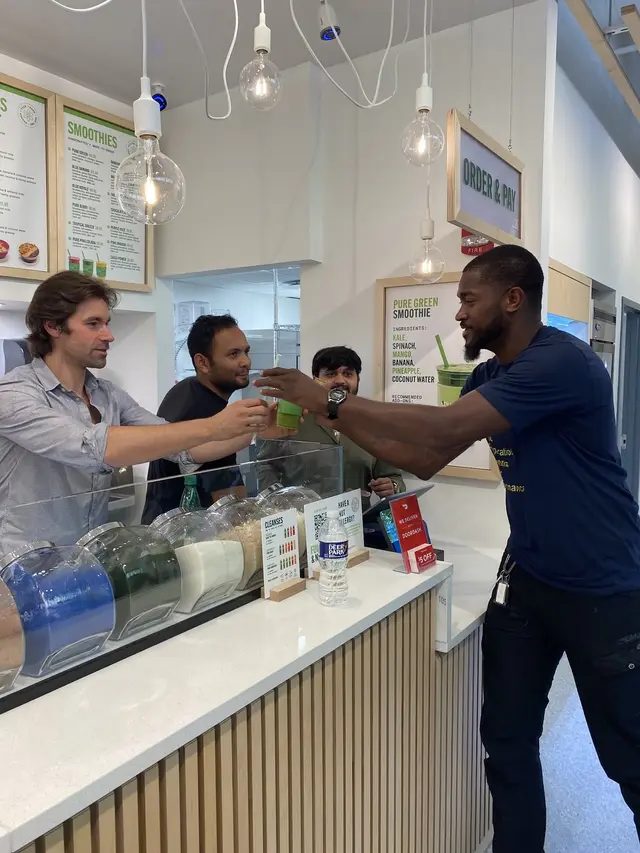 A team member handing a drink across the counter at Pure Green Charles Village