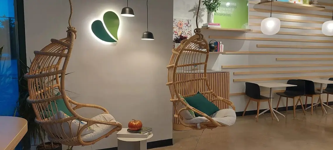 Hanging chairs under the glowing wall logo at Pure Green Oak Park