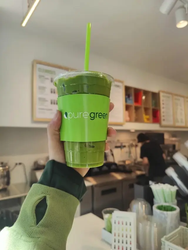 A green smoothie held up at the Pure Green Logan Square counter