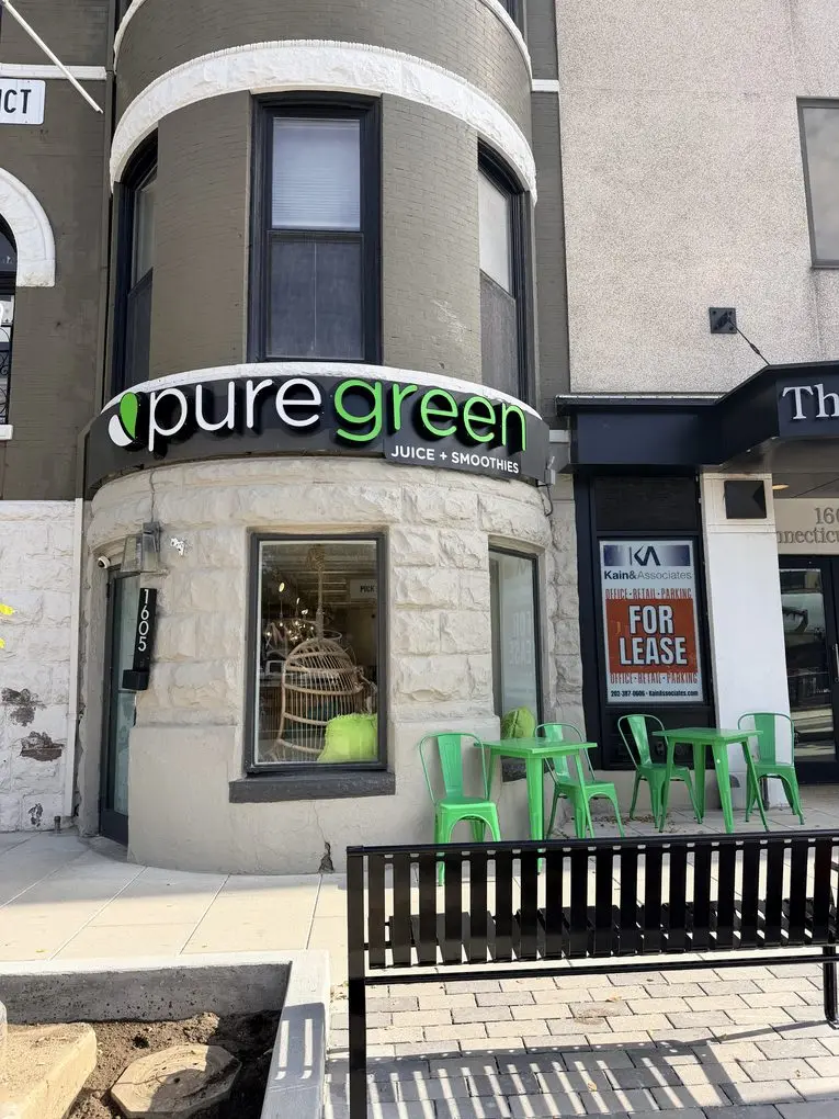 The Pure Green sign on the corner of 1605 Connecticut Avenue NW, with green chairs and tables outside