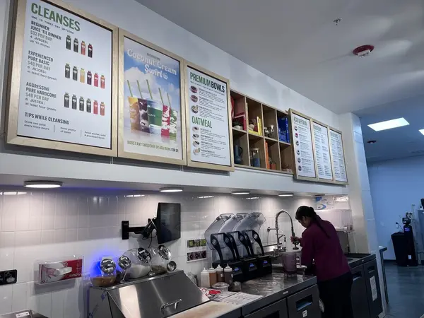 Team member making drinks under the menu boards at Pure Green Capitol Square