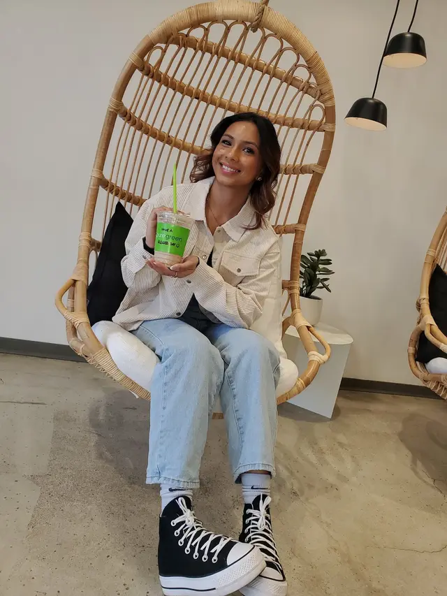 A guest with a smoothie in the hanging chair at Pure Green Buckhead Crossing