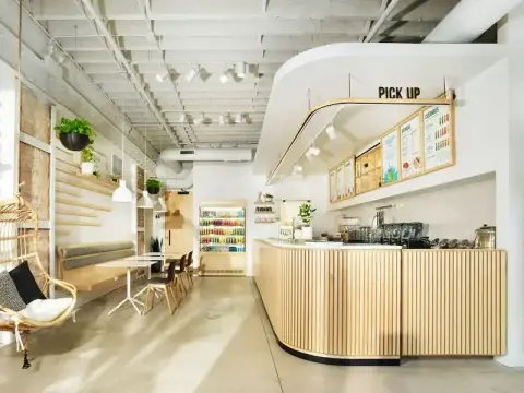 Inside Pure Green Fulton Market showing the wood-slat pickup counter, menu boards, and rattan seating area