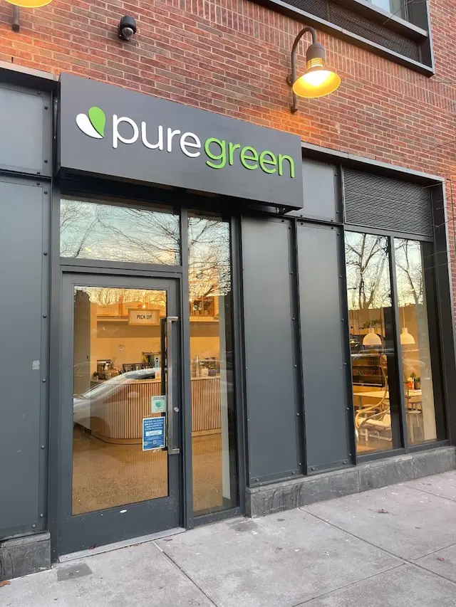 The lit shopfront of Pure Green Greenpoint at dusk