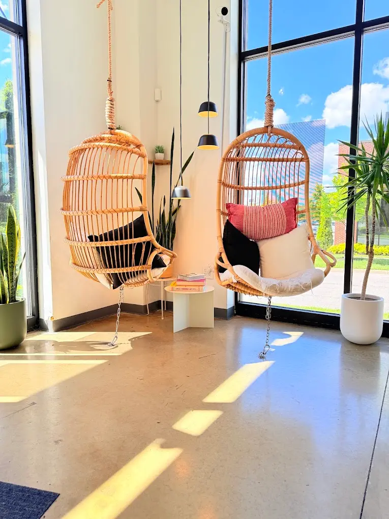 Two hanging rattan chairs in the sunlit window at Pure Green Westerville