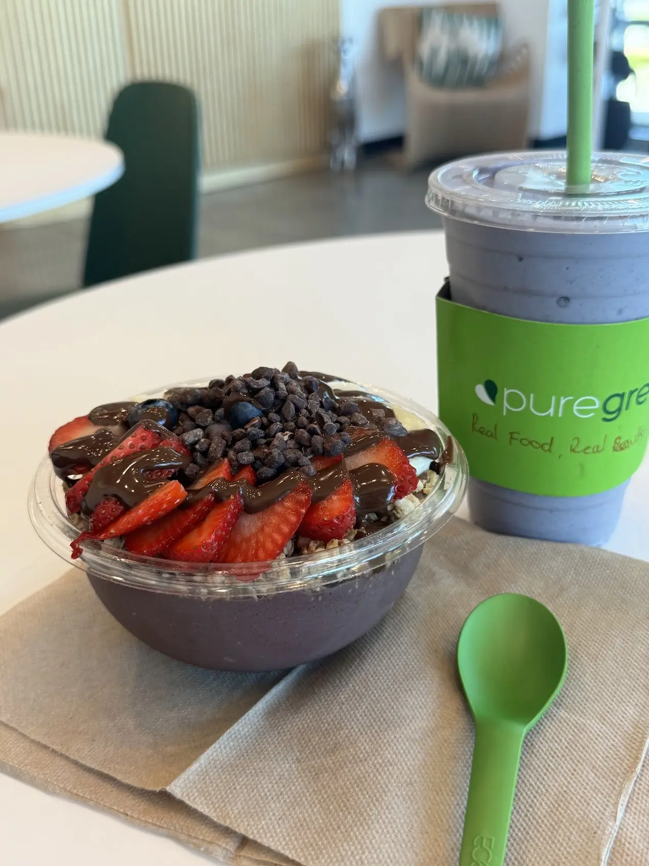 An acai bowl with strawberries and cacao nibs beside a smoothie at Pure Green Fort Myers