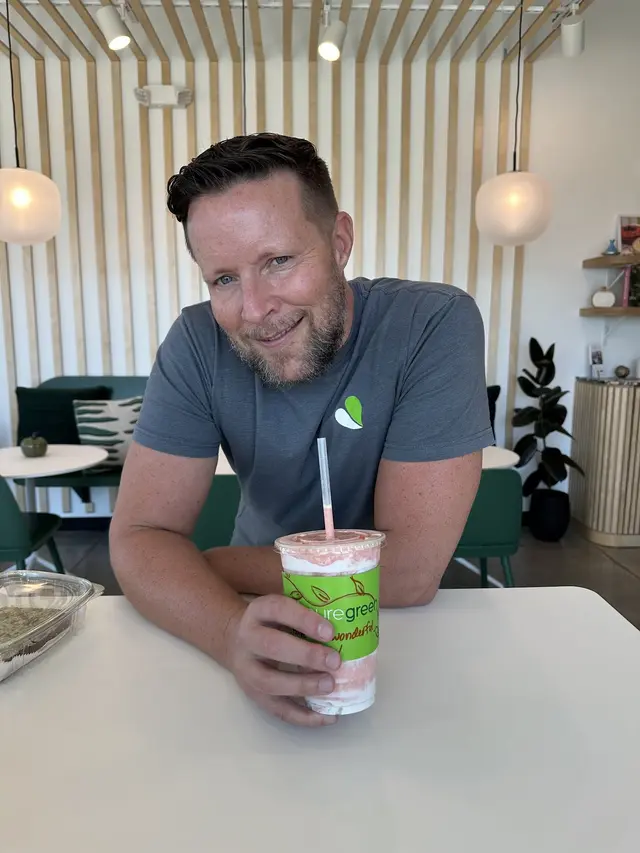 A guest with a smoothie at a table inside Pure Green Fort Myers