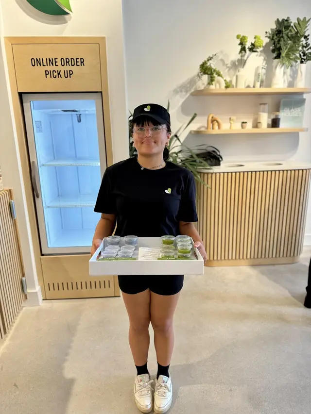 A team member by the online order pickup fridge at Pure Green Deerfield