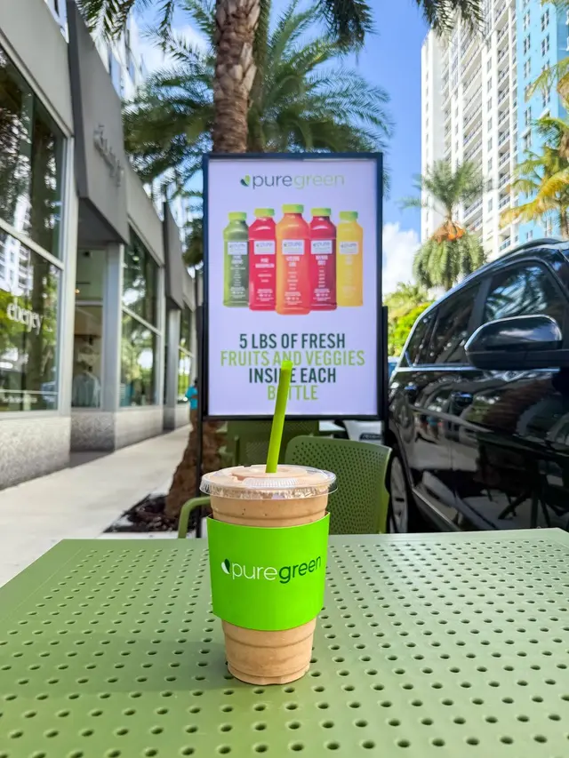 A Pure Green smoothie on the patio table with the Miami Beach skyline behind