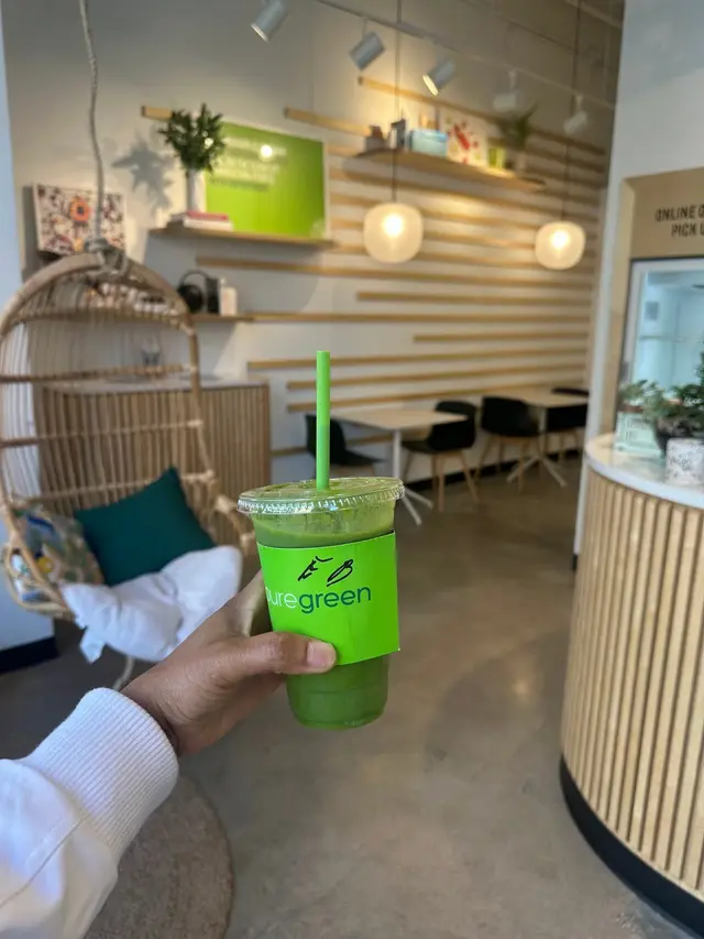 A green smoothie held up by the seating area at Pure Green Oak Park