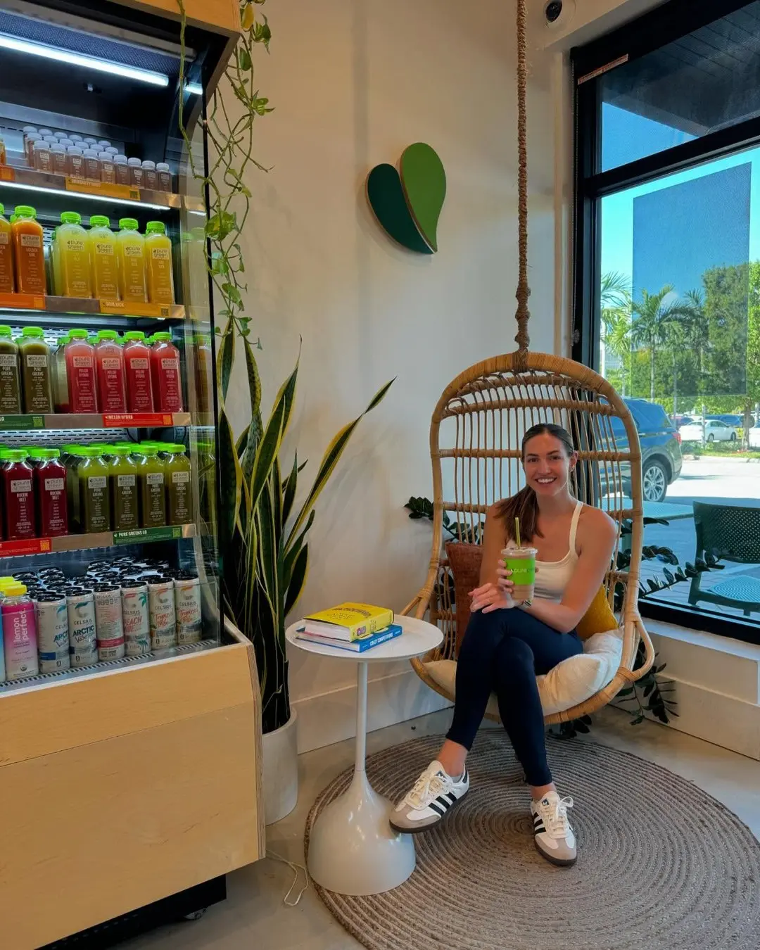Guest relaxing in the rattan hanging chair beside the juice fridge at Pure Green Aventura