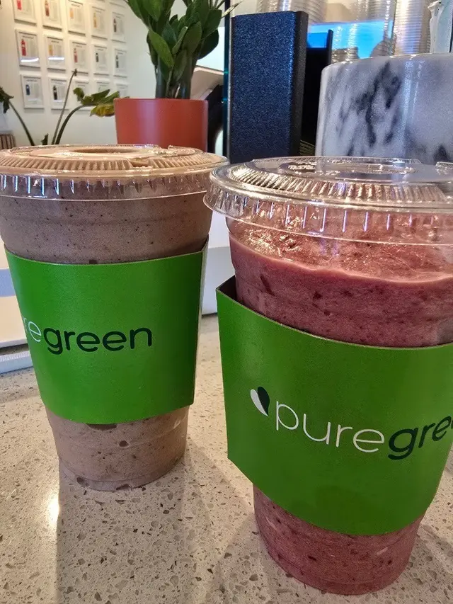 Two blended Pure Green drinks in branded cups on the counter