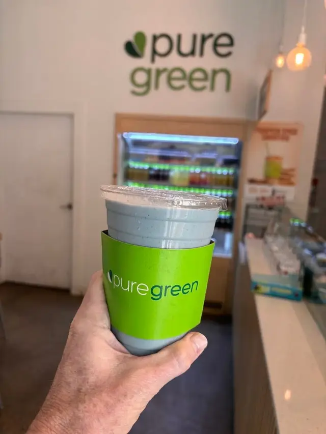 A guest holding a Pure Green smoothie inside the Bed-Stuy store