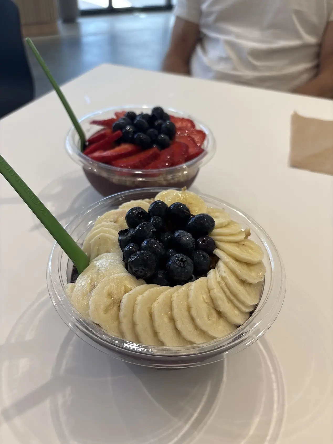 Two acai bowls topped with banana, blueberries and strawberries at Pure Green North Naples