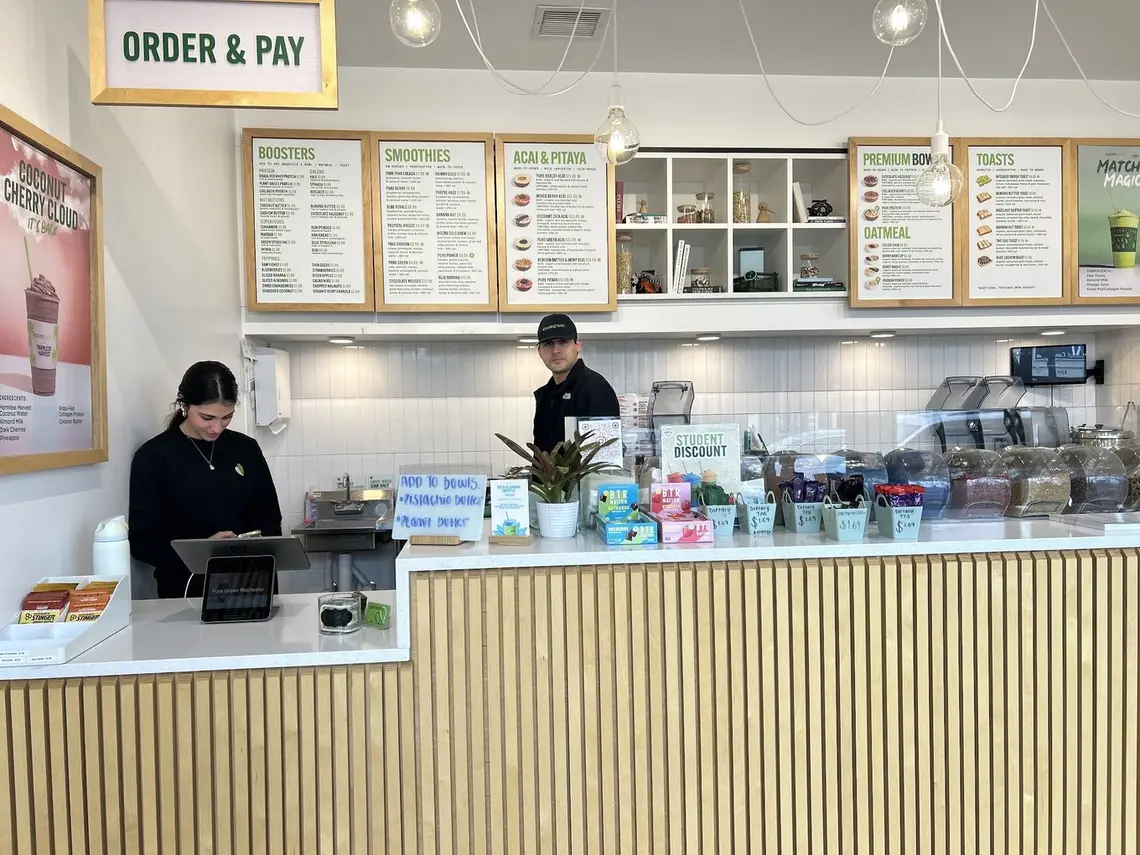 Two team members behind the order counter at Pure Green Downtown Rochester