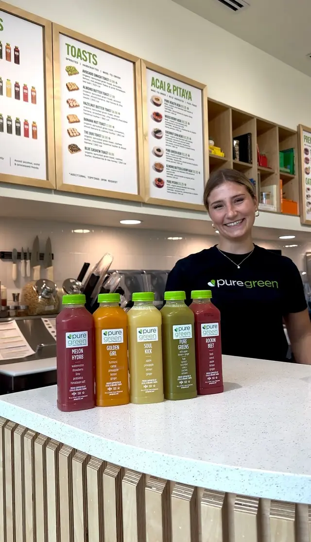 A team member behind the counter under the menu boards at Pure Green North Naples
