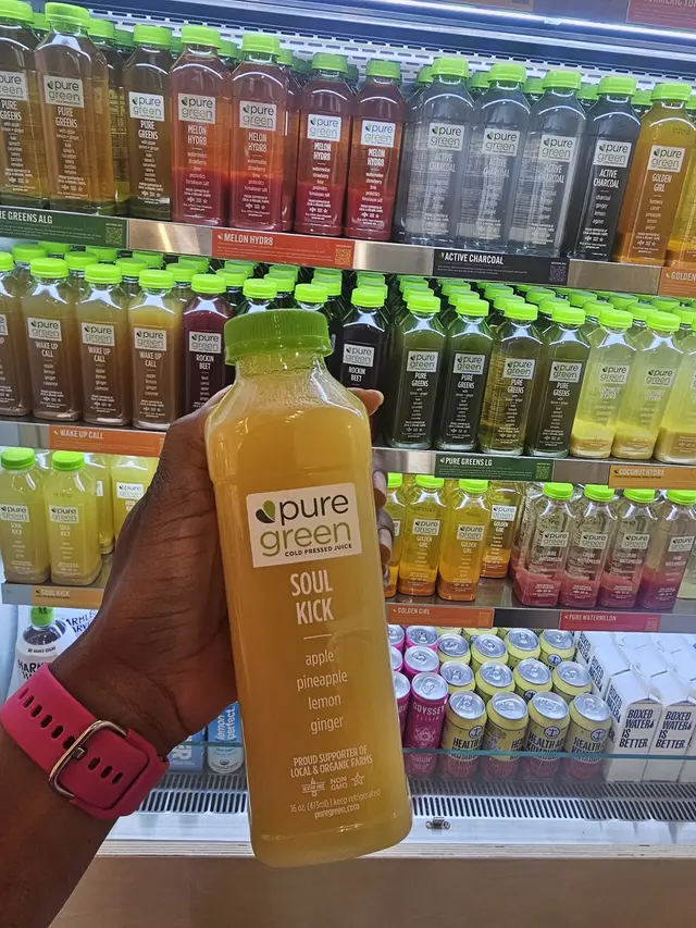 A Soul Kick cold-pressed juice held up by the fridge at Pure Green South Michigan Ave