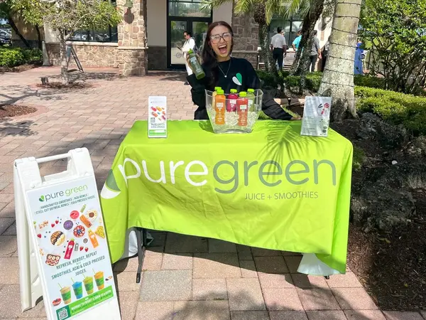 Pure Green Coral Springs team member at a cold-pressed juice pop-up table