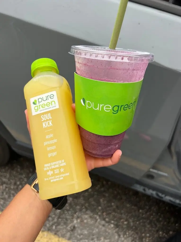 A guest holding a cold-pressed juice and a smoothie at Pure Green Sterling Heights