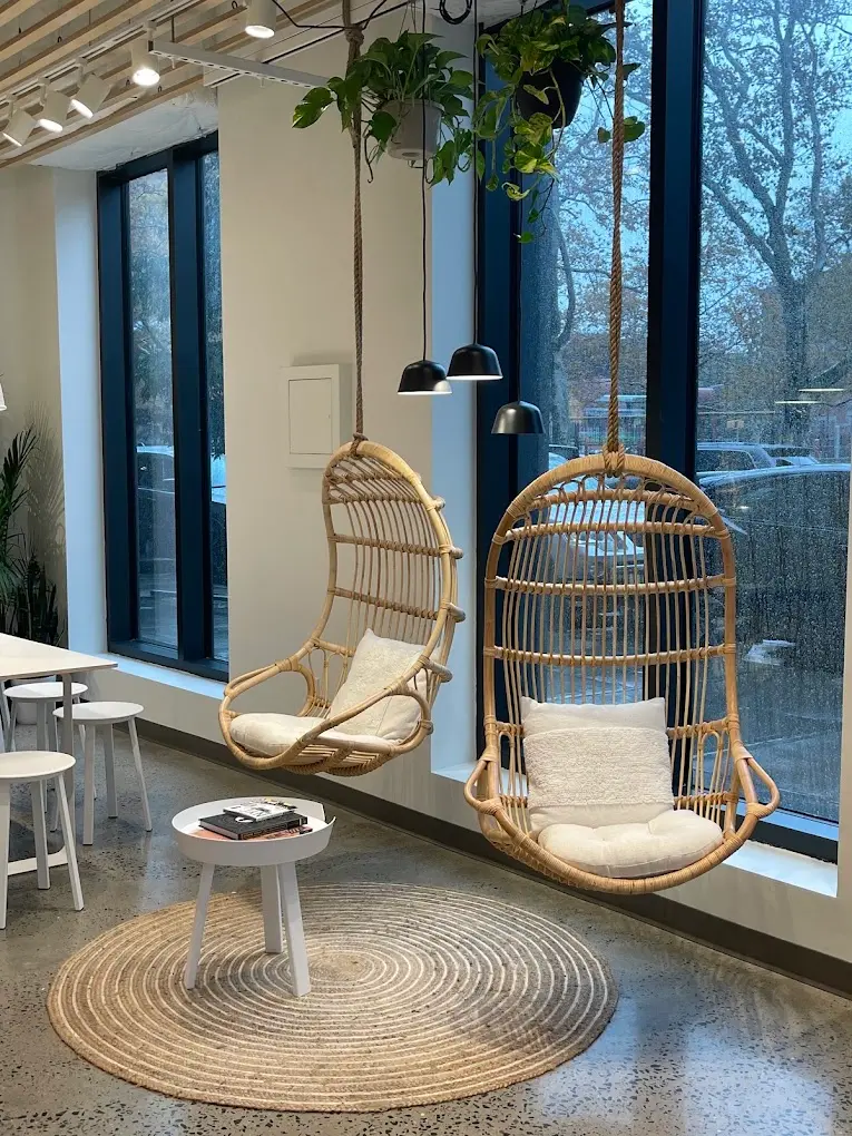 Two hanging rattan chairs at the window inside Pure Green Greenpoint