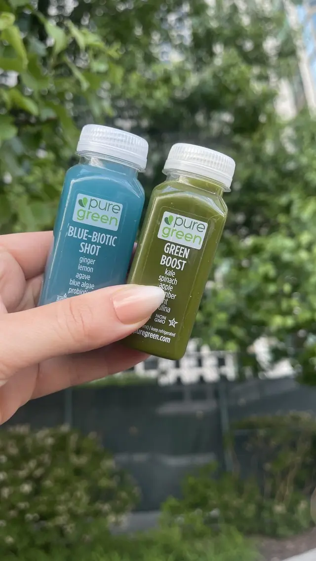Blue-Biotic and Green Boost cold-pressed shots held up outside Pure Green River North