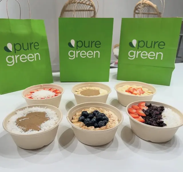 Six oatmeal and acai bowls laid out with Pure Green bags at Pure Green Deerfield