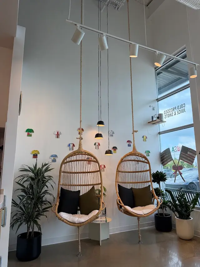 Two hanging rattan chairs below the jersey wall inside Pure Green Frisco