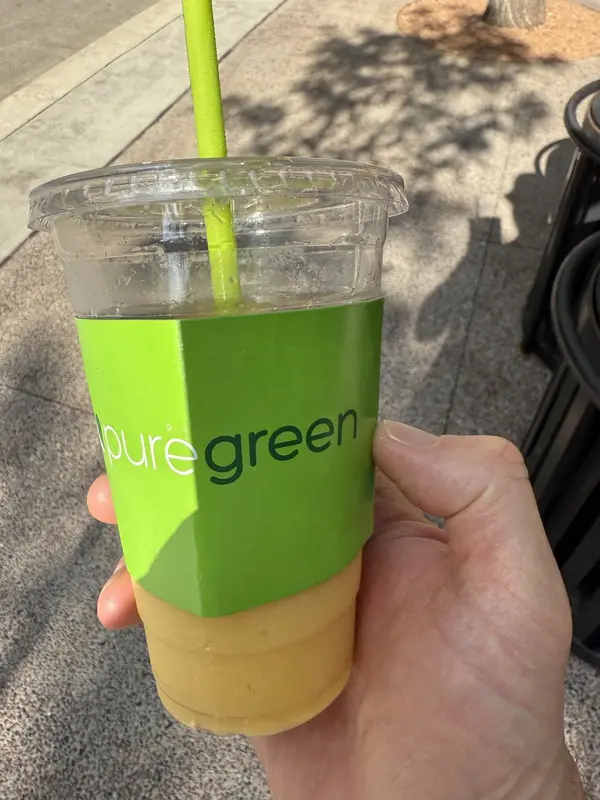 Pure Green Capitol Square smoothie held up outside the store