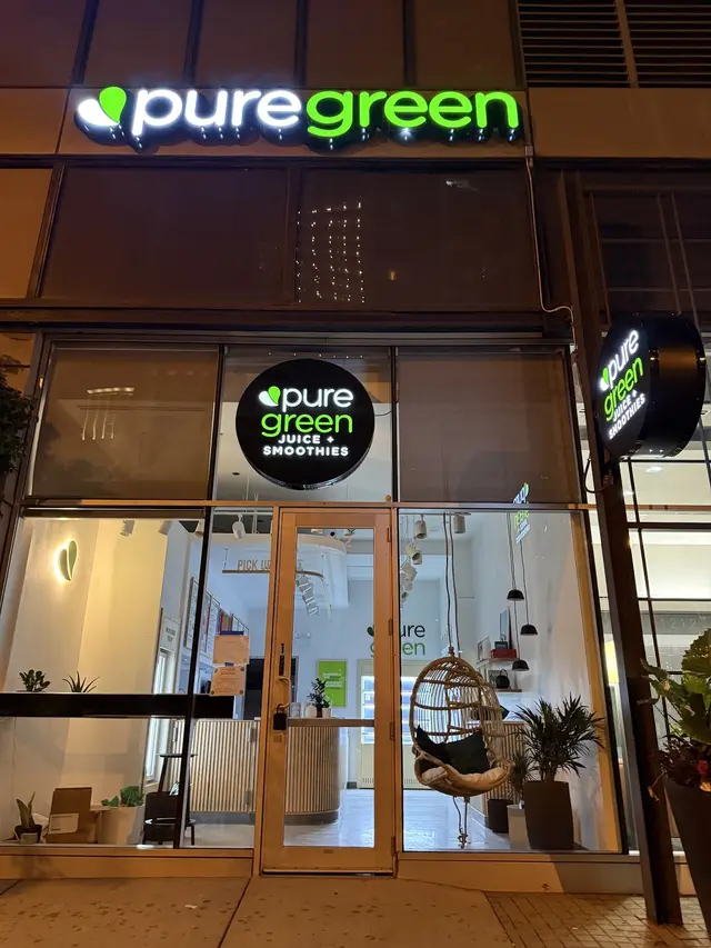 The lit Pure Green sign above the South Michigan Avenue storefront at night