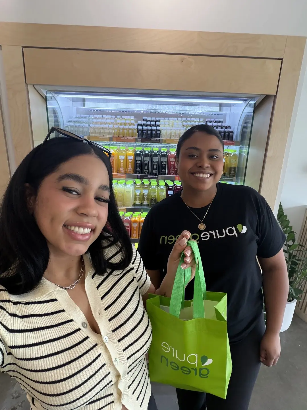 Guest and team member with a Pure Green bag at the Miami Lakes juice fridge