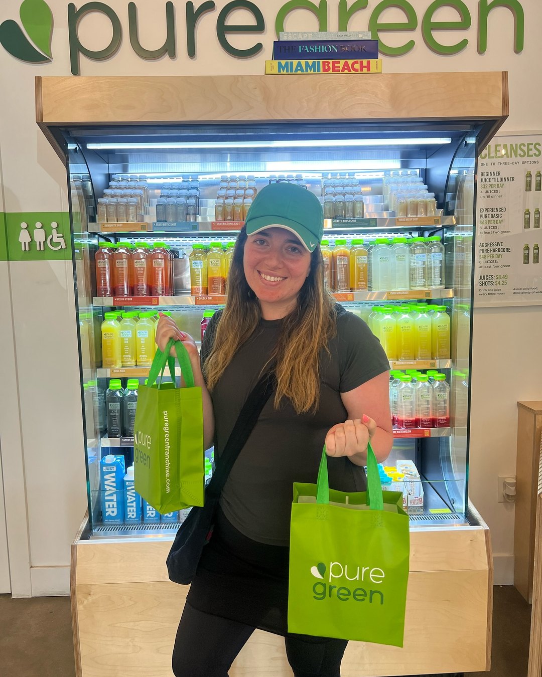Guest with Pure Green bags by the cold-pressed juice fridge at the Garden Shops store