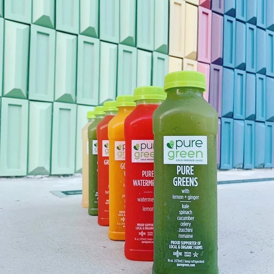 Colorful cold-pressed juices lined up outside Pure Green Garden Shops
