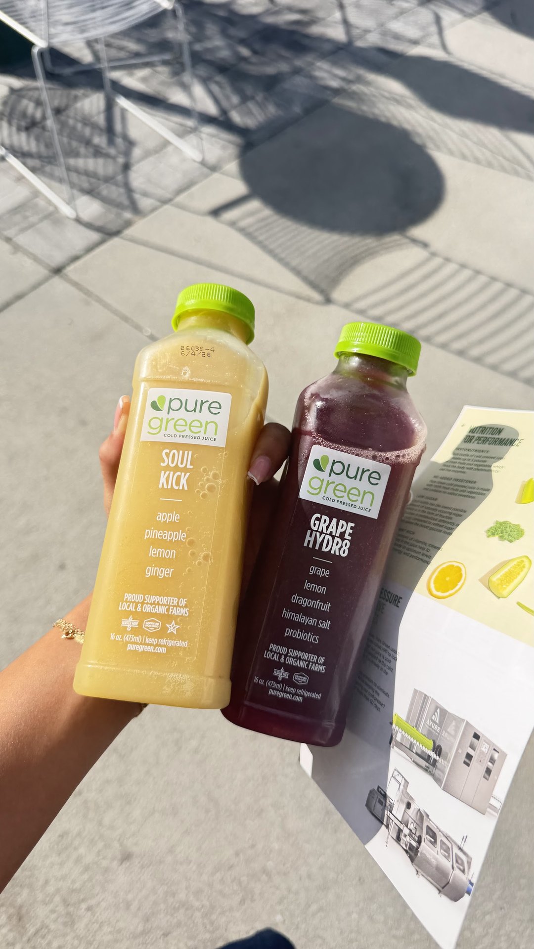 Guest holding Soul Kick and Grape Hydrate cold-pressed juices outside Pure Green Cape Coral