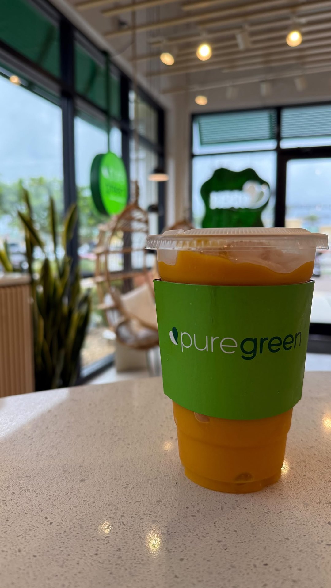 Iced Pure Green smoothie on the counter with the Cape Coral storefront behind