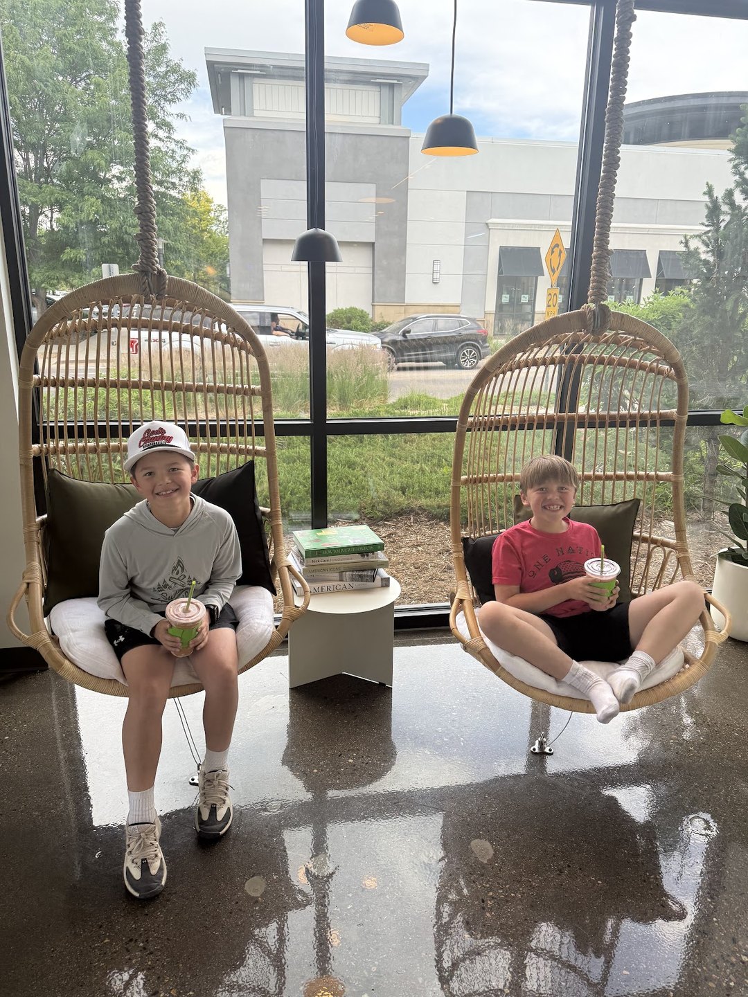 Kids relaxing in the rattan hanging chairs outside Pure Green Fort Collins