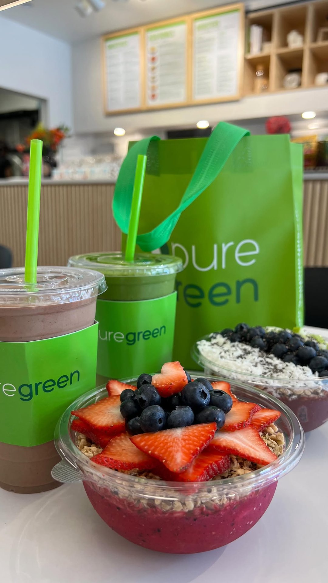 Pure Green smoothies and an acai bowl with a Pure Green bag at the Fulton Market juice bar