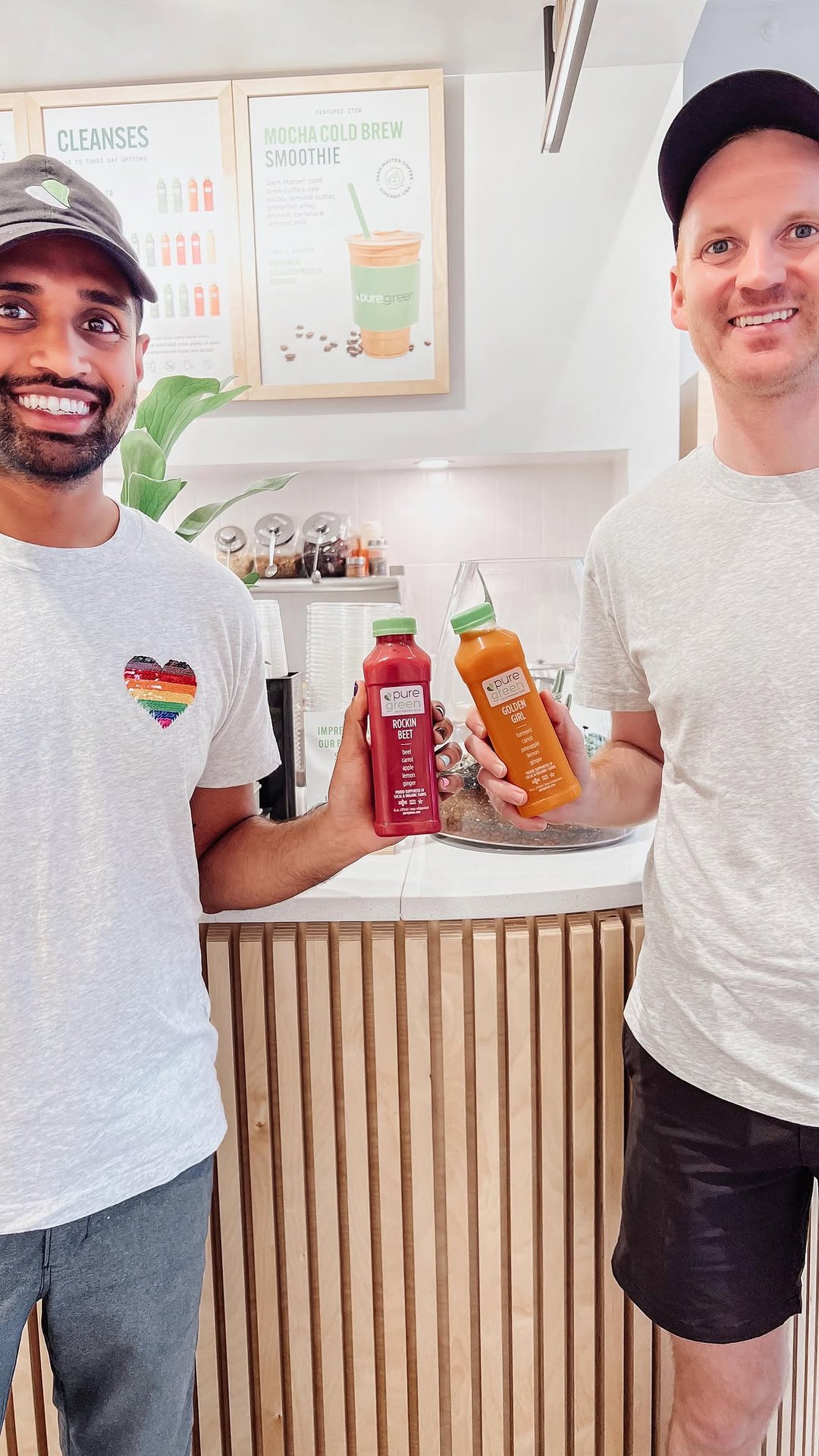Team members holding fresh cold-pressed juices at the Pure Green Fulton Market counter