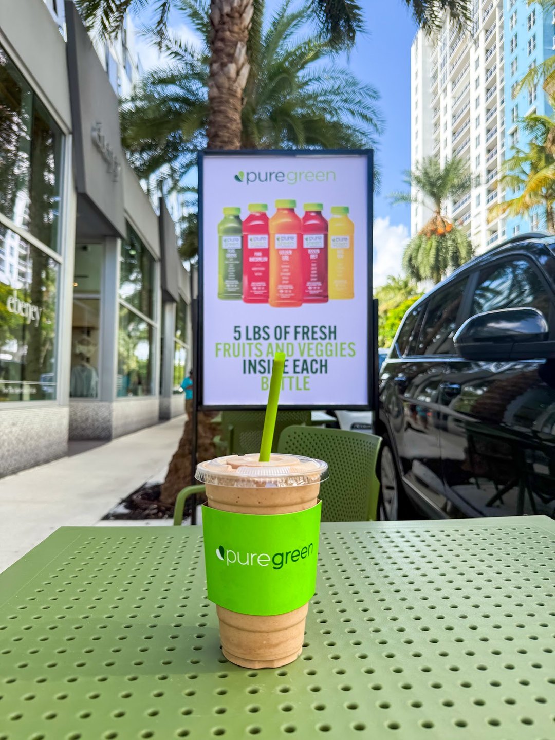 A Pure Green smoothie on the patio table with the Miami Beach skyline behind