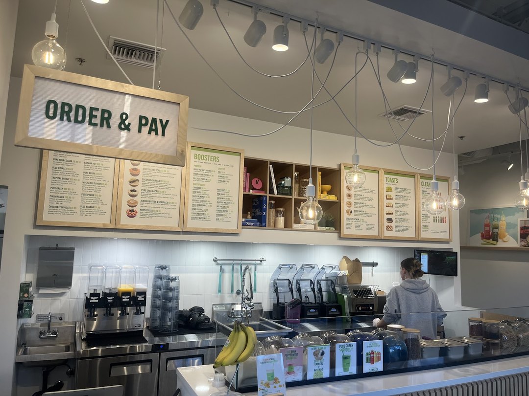 The Order & Pay counter and menu boards inside Pure Green Tempe with a team member preparing orders