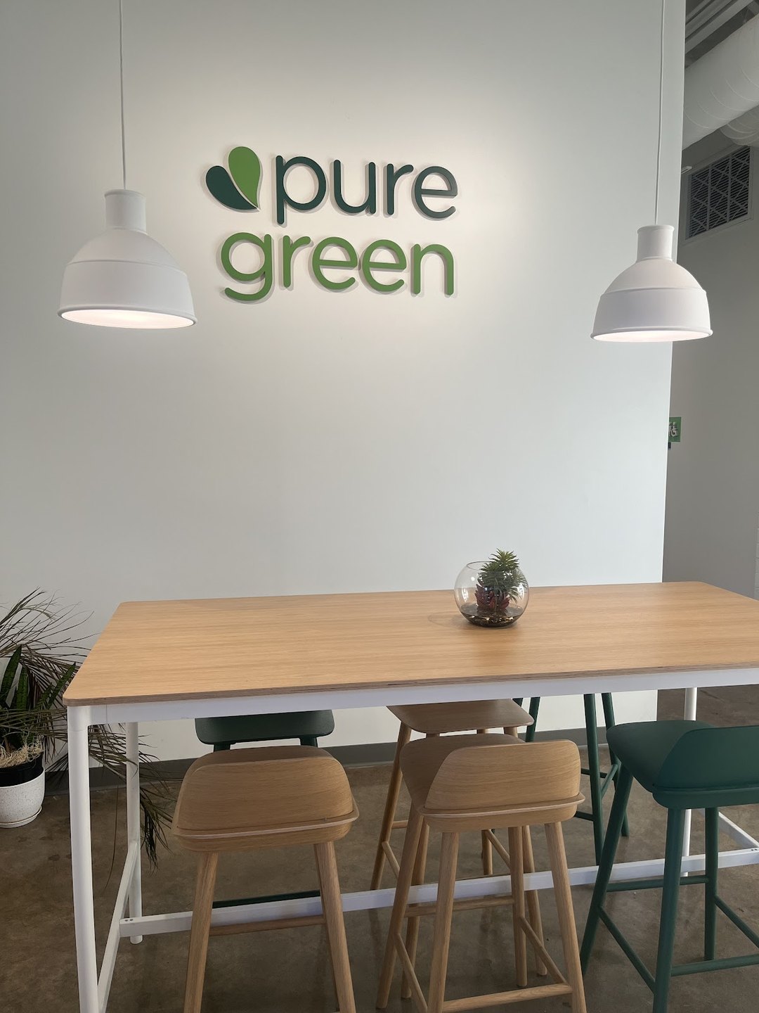 Inside Pure Green Tempe showing the pure green wall logo and communal seating