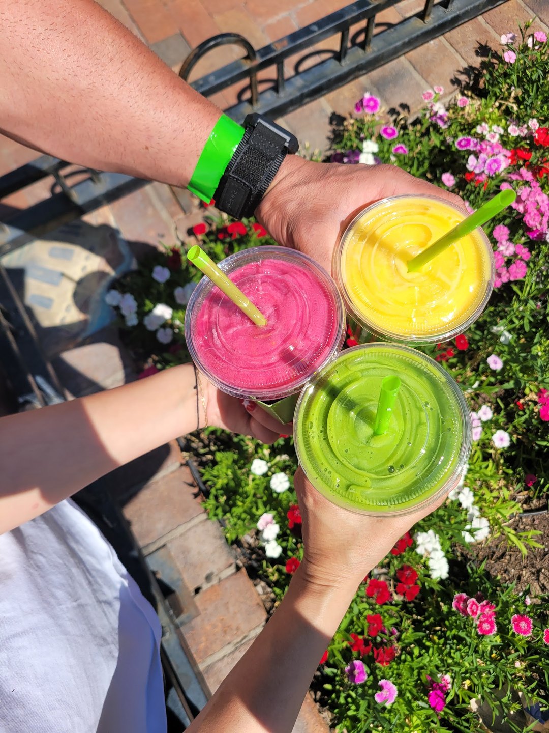 Three colorful Pure Green smoothies raised together in a toast