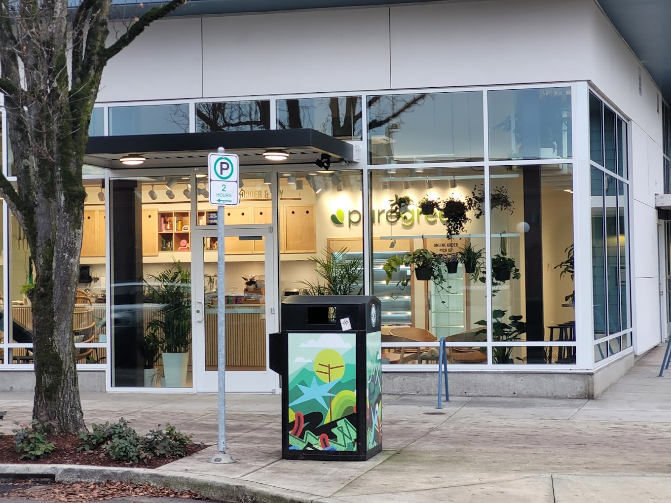 The lit shopfront of Pure Green Portland on SE Milwaukie Avenue at dusk